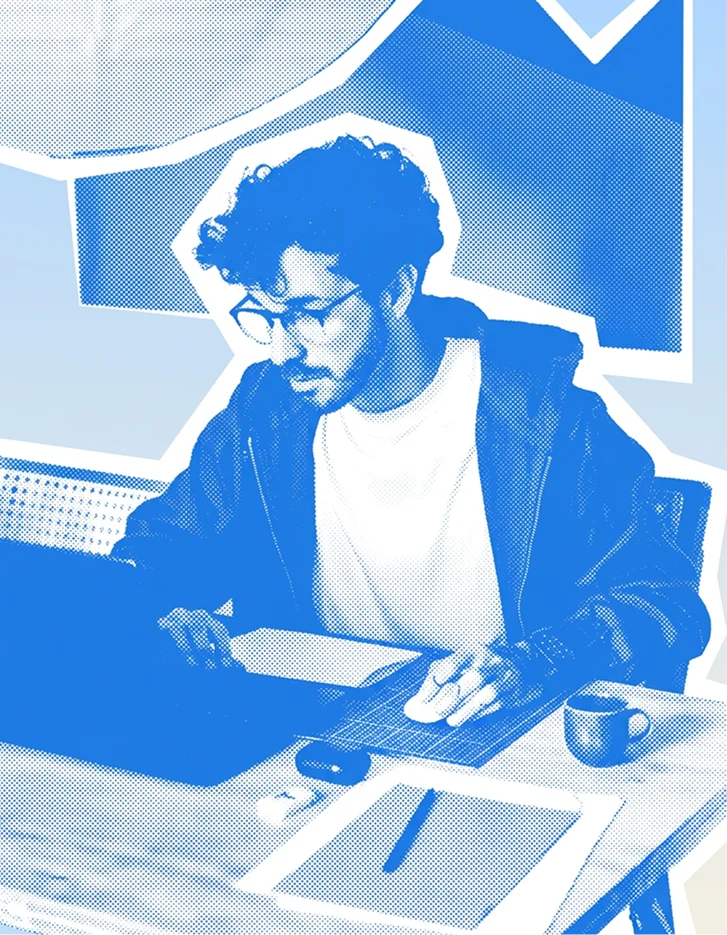 Guilherme Santiago at a desk, marking up a printed layout next to an open laptop, in a blue duotone treatment.